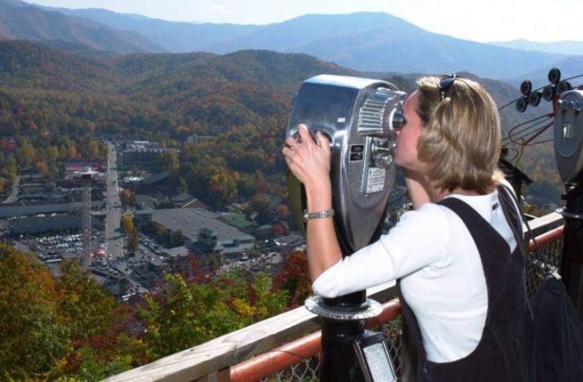 Women looking through viewfinder in mountains.